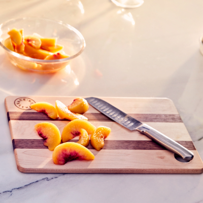 Sliced peaches on a cutting board next to a knife
