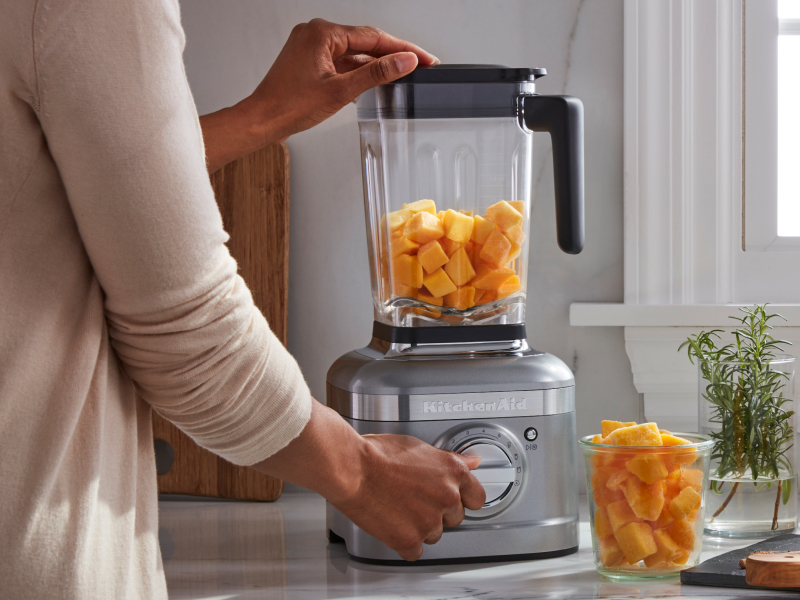 Person blending pumpkin in a KitchenAid® blender