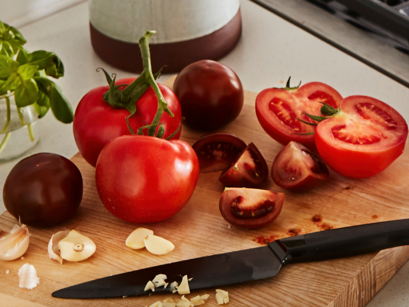 A cutting board piled with tomatoes A cutting board piled with tomatoes