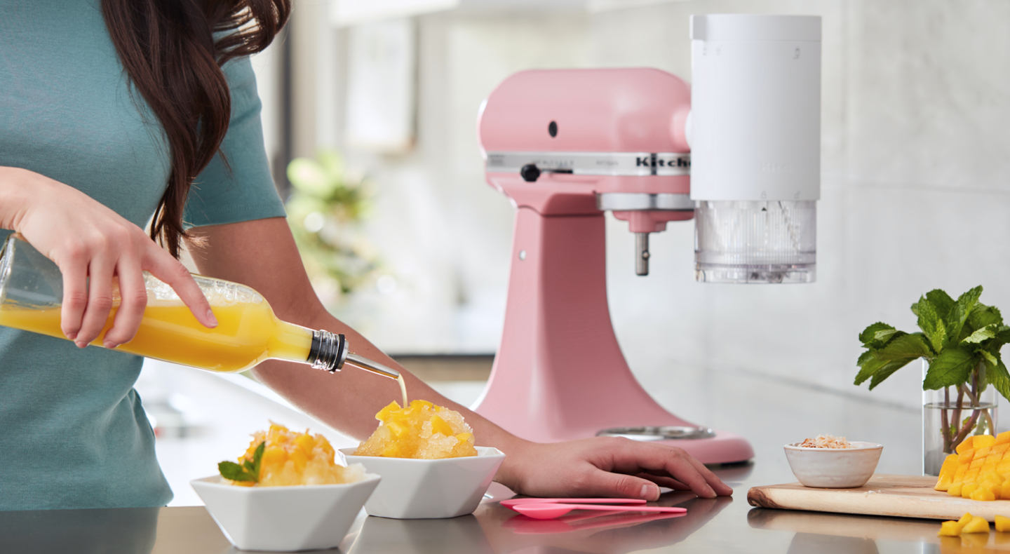 Orange syrup being poured on a bowl of shave ice