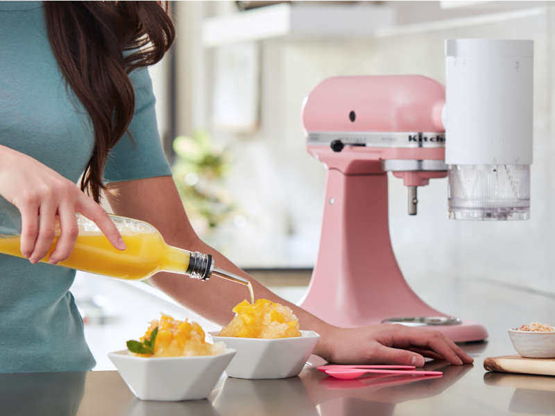 Orange syrup being poured on a bowl of shave ice