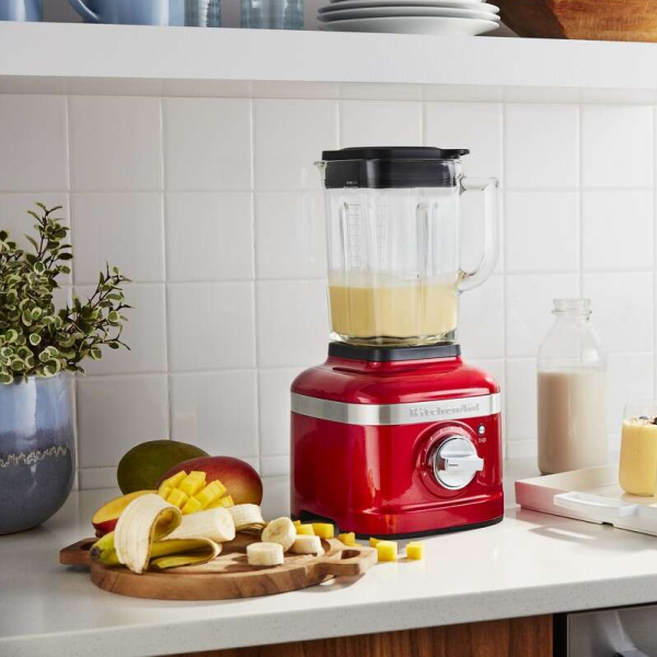 Red KitchenAid® blender next to sliced bananas on a cutting board