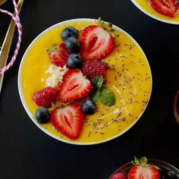 Mango smoothie bowl topped with sliced berries