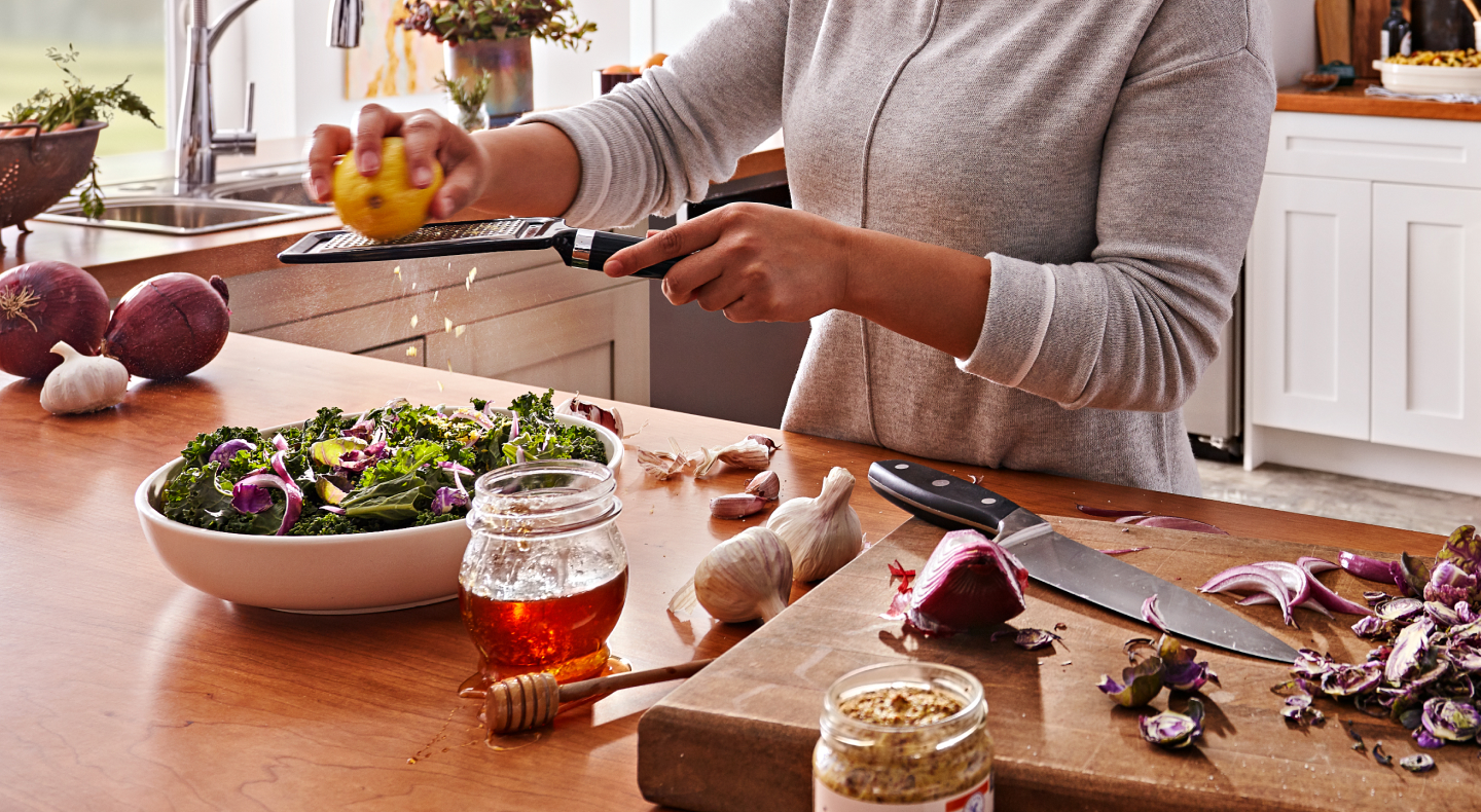 Woman grating citrus over salad Woman grating citrus over salad