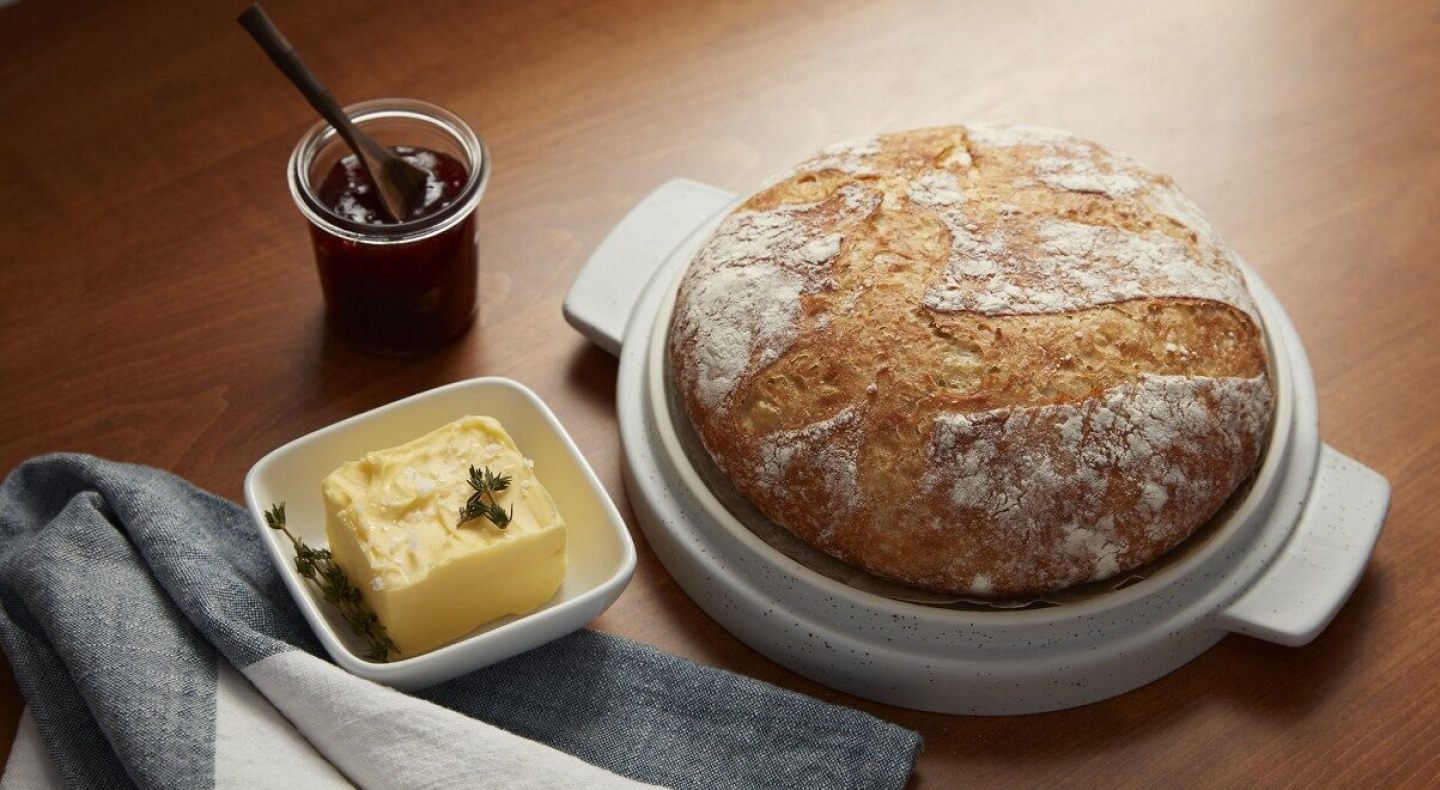 Round sourdough loaf next to a garnished butter dish and jar of jam spread Round sourdough loaf next to a garnished butter dish and jar of jam spread