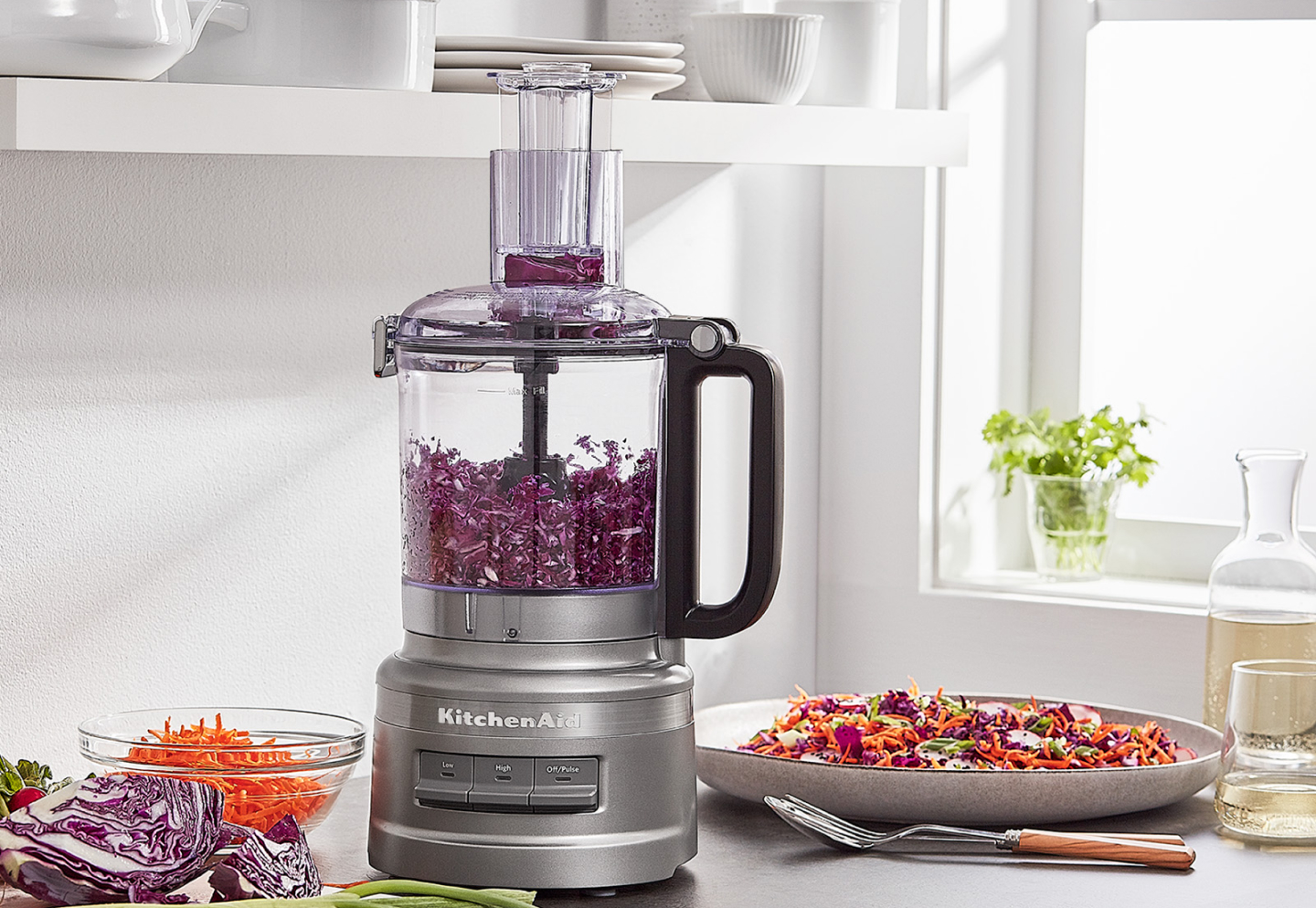 Shredded purple cabbage in a KitchenAid® food processor on a kitchen counter next to a plate of food Shredded purple cabbage in a KitchenAid® food processor on a kitchen counter next to a plate of food