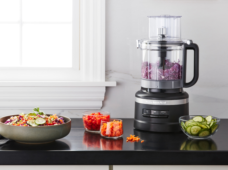 Shredded purple cabbage in a KitchenAid® food processor on a kitchen counter next to other shredded vegetables Shredded purple cabbage in a KitchenAid® food processor on a kitchen counter next to other shredded vegetables