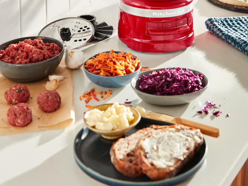 Modern kitchen counter with a bowl of shredded purple cabbage, shredded carrots, garlic cloves, meatballs and a plate of bread with a creamy spread Modern kitchen counter with a bowl of shredded purple cabbage, shredded carrots, garlic cloves, meatballs and a plate of bread with a creamy spread