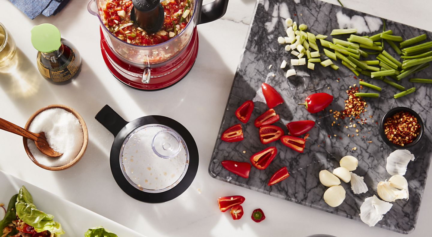 Vegetables on a cutting board next to a KitchenAid® food chopper
