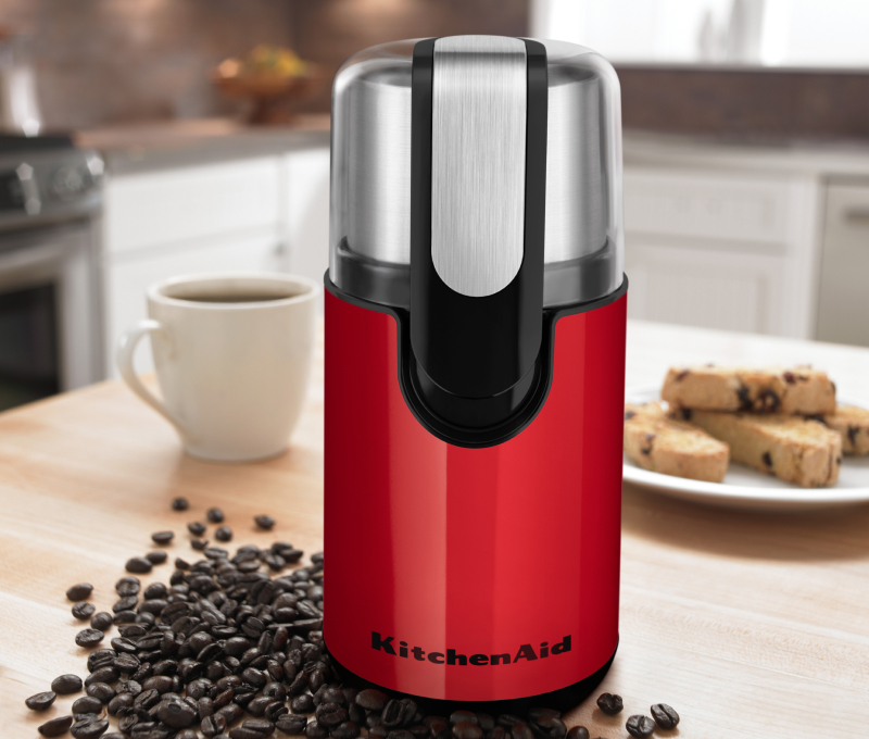Red coffee grinder on a countertop with beans Red coffee grinder on a countertop with beans