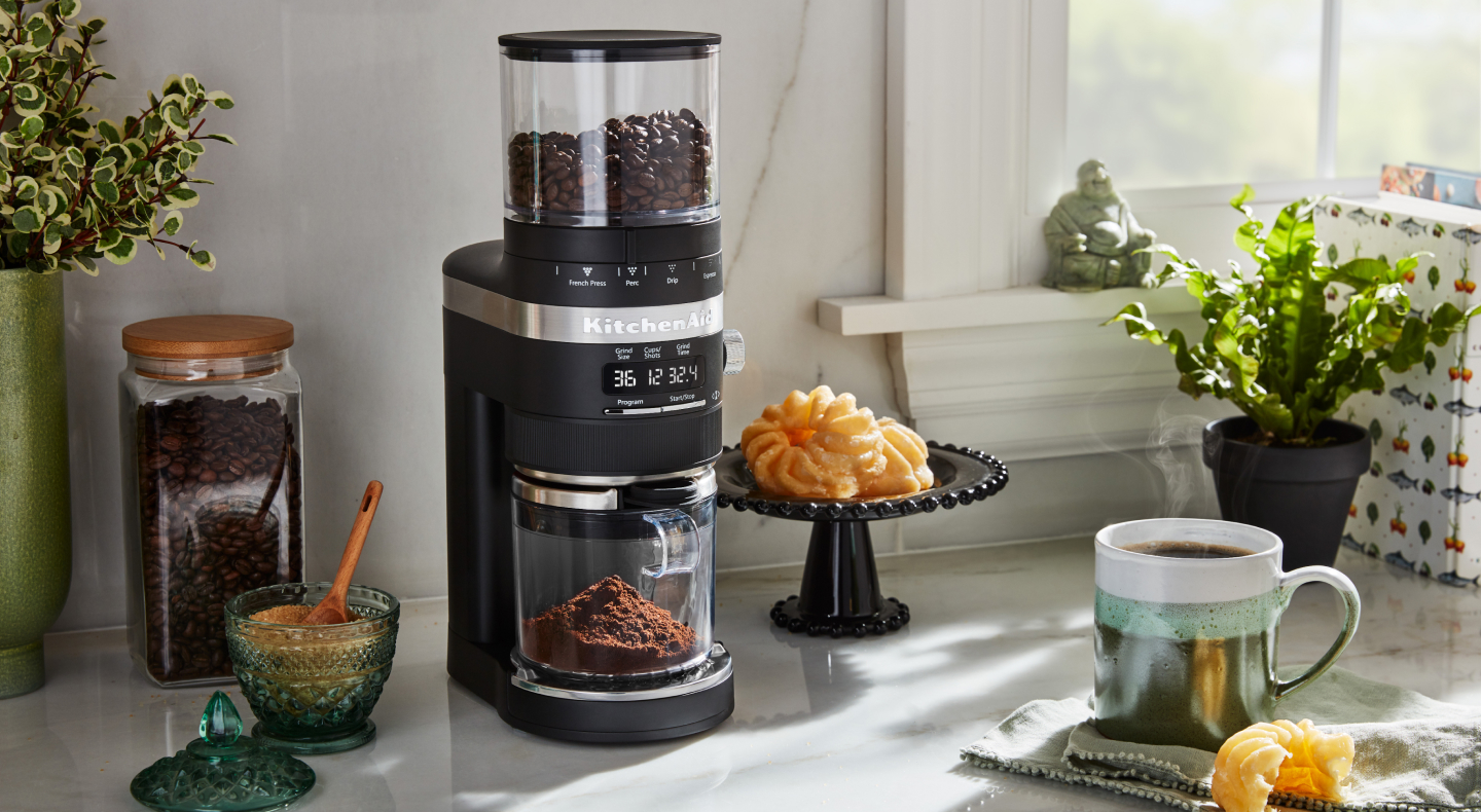 Burr grinder on a counter with pastries and brewed coffee Burr grinder on a counter with pastries and brewed coffee