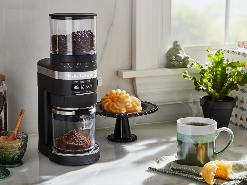 Burr grinder on a counter with pastries and brewed coffee Burr grinder on a counter with pastries and brewed coffee