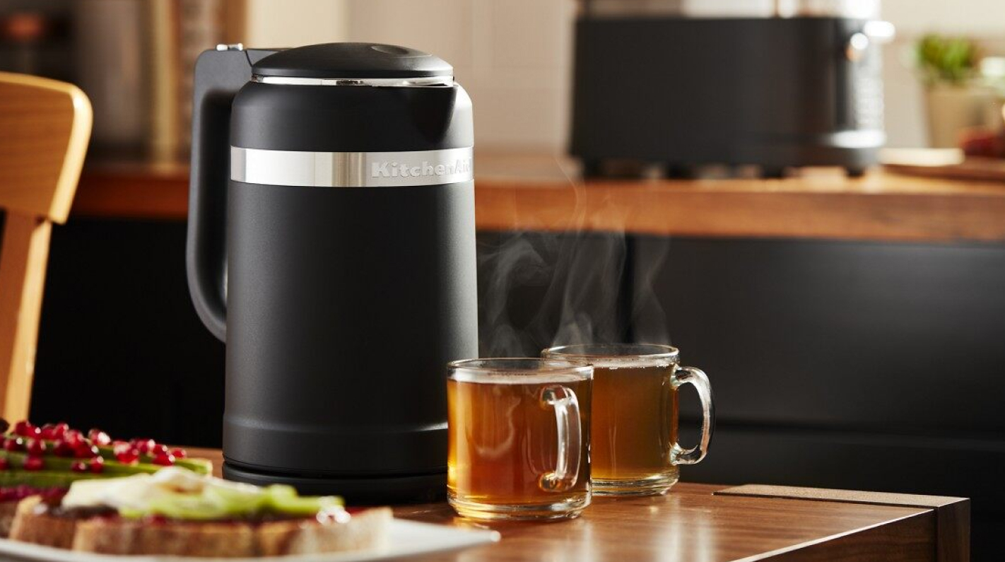 Black KitchenAid® electric tea kettle on table with glasses of tea. Black KitchenAid® electric tea kettle on table with glasses of tea.