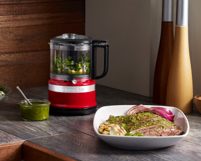 Red food chopper on counter filled with ingredients
