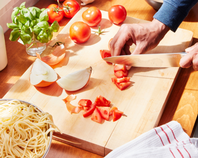 Person chopping tomatoes on a cutting board