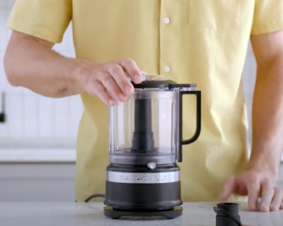 Person placing lid on black food chopper