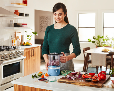 Person pulsing red onions in a blue food chopper