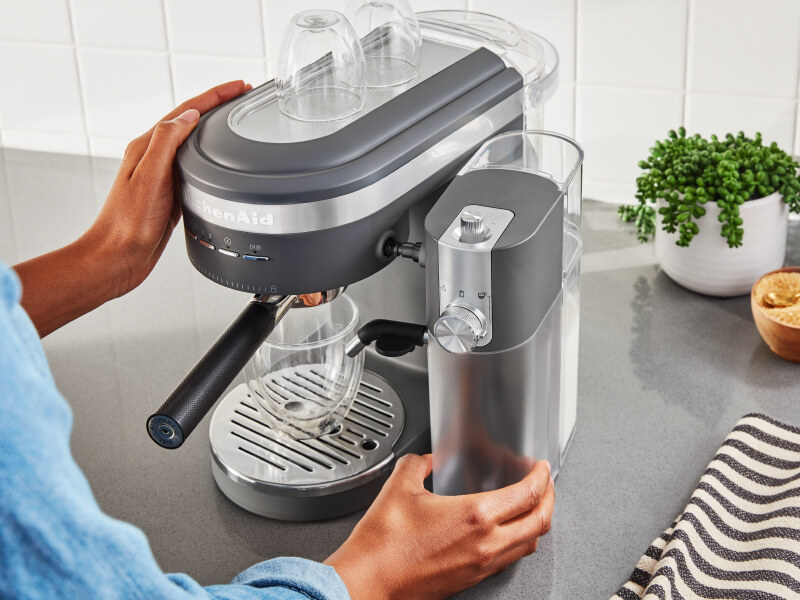 Person placing an espresso machine water tank onto an espresso machine