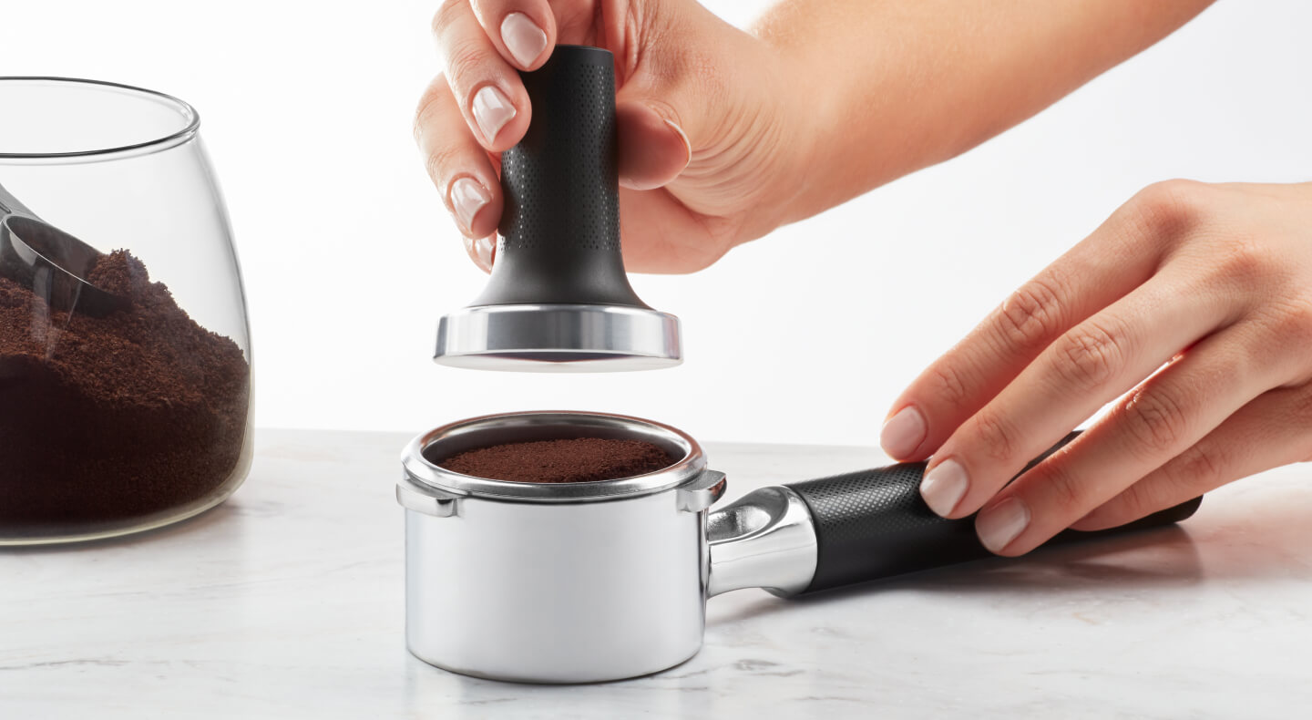 Hand tamping espresso grounds in a portafilter Hand tamping espresso grounds in a portafilter