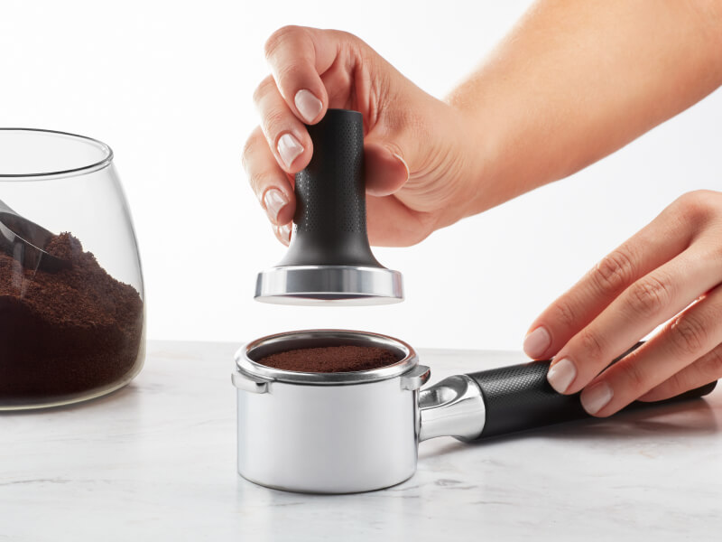 Hand tamping espresso grounds in a portafilter Hand tamping espresso grounds in a portafilter