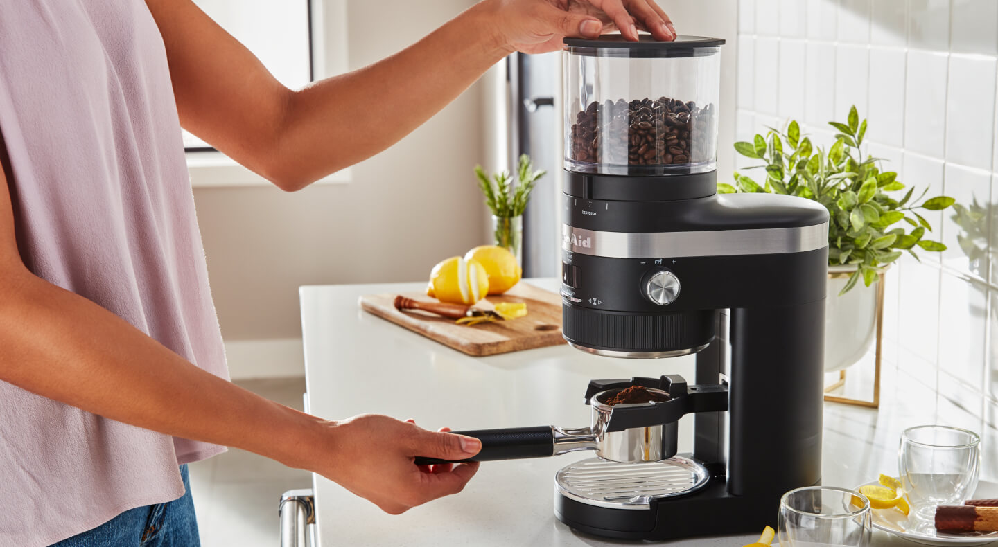 Woman grinding coffee into a portafilter Woman grinding coffee into a portafilter