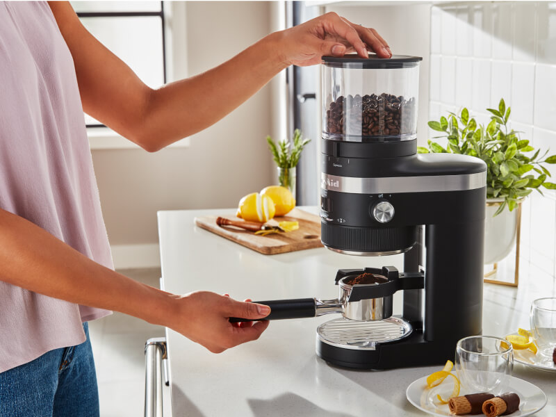 Woman grinding coffee into a portafilter Woman grinding coffee into a portafilter
