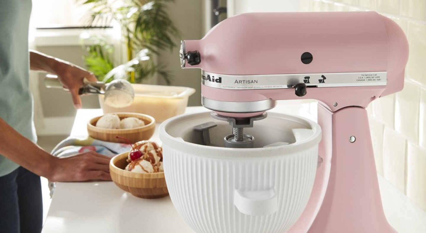 Person making an ice cream sundae next to a pink KitchenAid® stand mixer Person making an ice cream sundae next to a pink KitchenAid® stand mixer