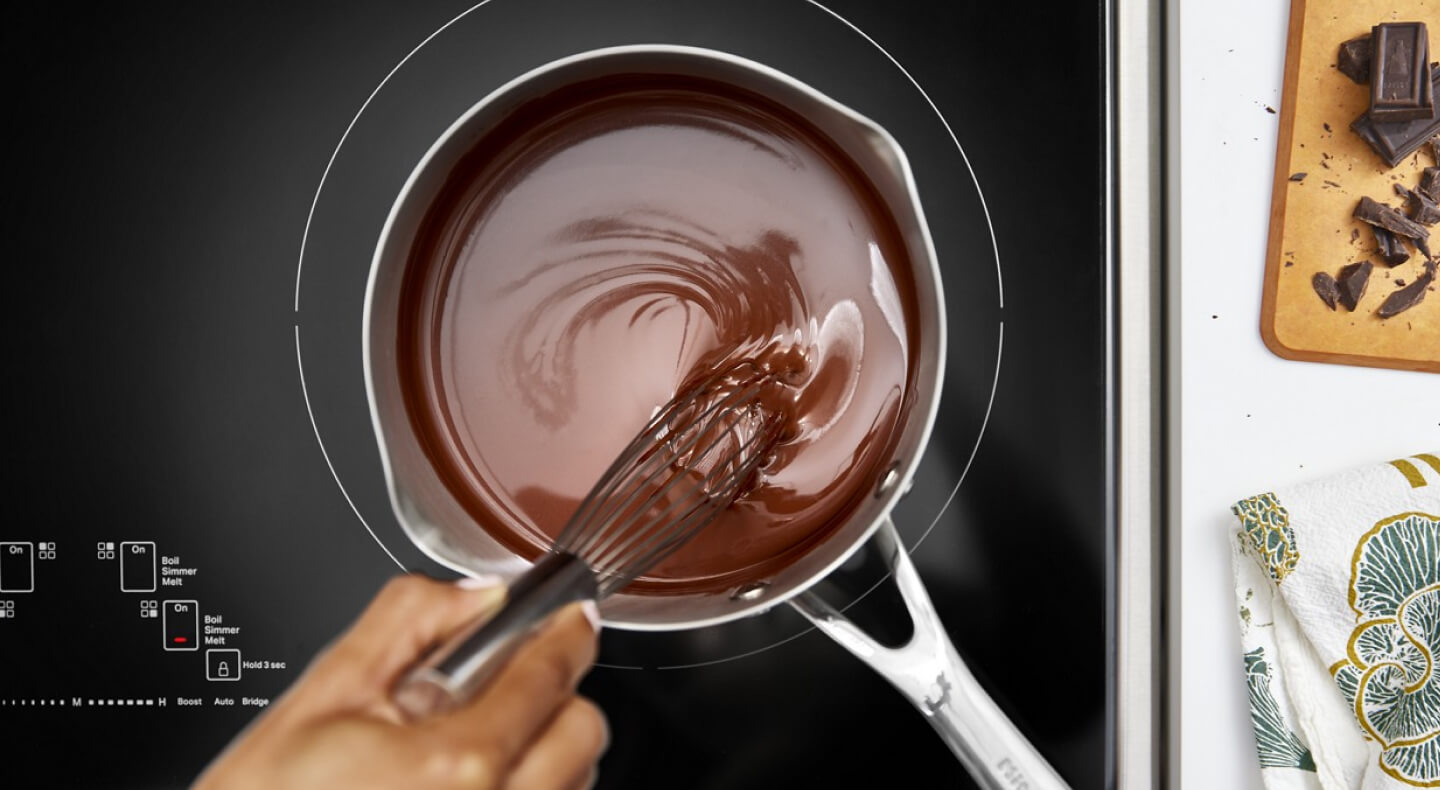 Person melting chocolate on an electric cooktop