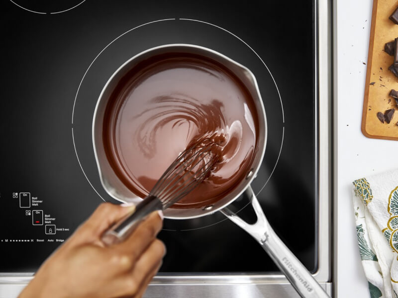 Person melting chocolate on an electric cooktop