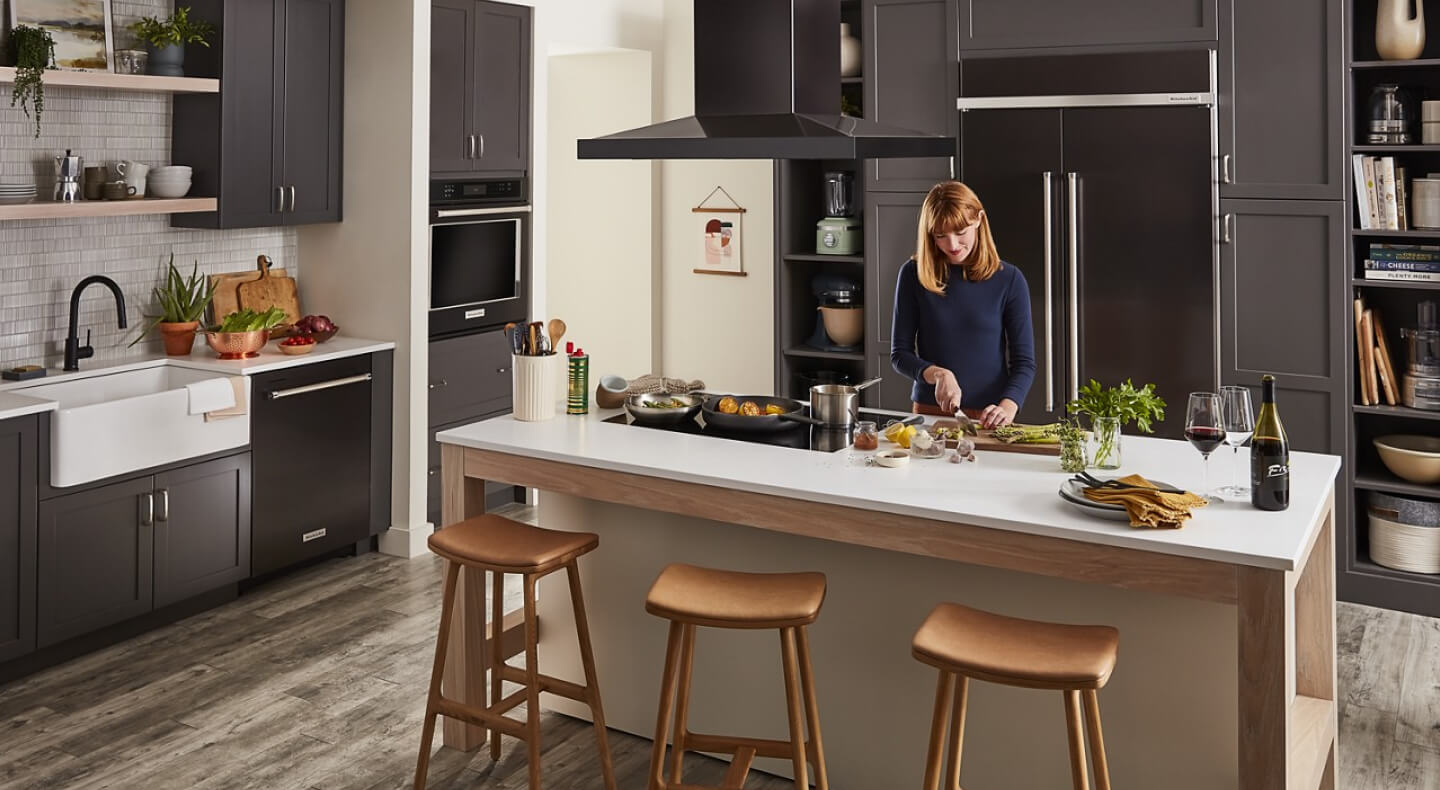 A woman chopping vegetables at an island in a spacious kitchen