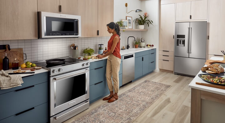 A woman prepping food to the right of her stainless steel range A woman prepping food to the right of her stainless steel range