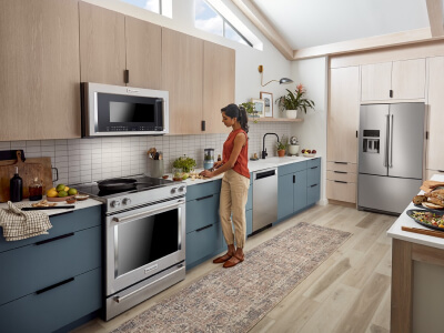 A woman prepping food to the right of her stainless steel range A woman prepping food to the right of her stainless steel range