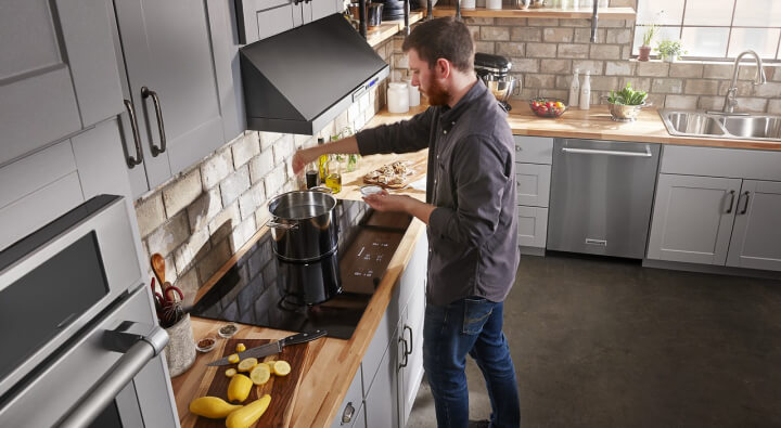 A man cooks in his kitchen using his electric cooktop