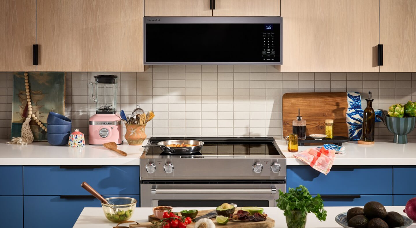 Electric range below a low profile microwave in a kitchen with tan cabinetry Electric range below a low profile microwave in a kitchen with tan cabinetry