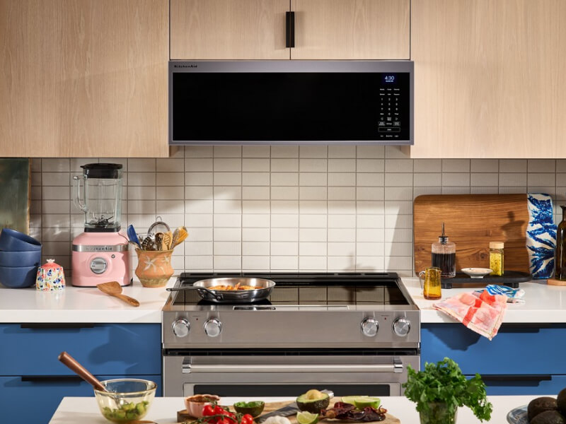 Electric range below a low profile microwave in a kitchen with tan cabinetry Electric range below a low profile microwave in a kitchen with tan cabinetry