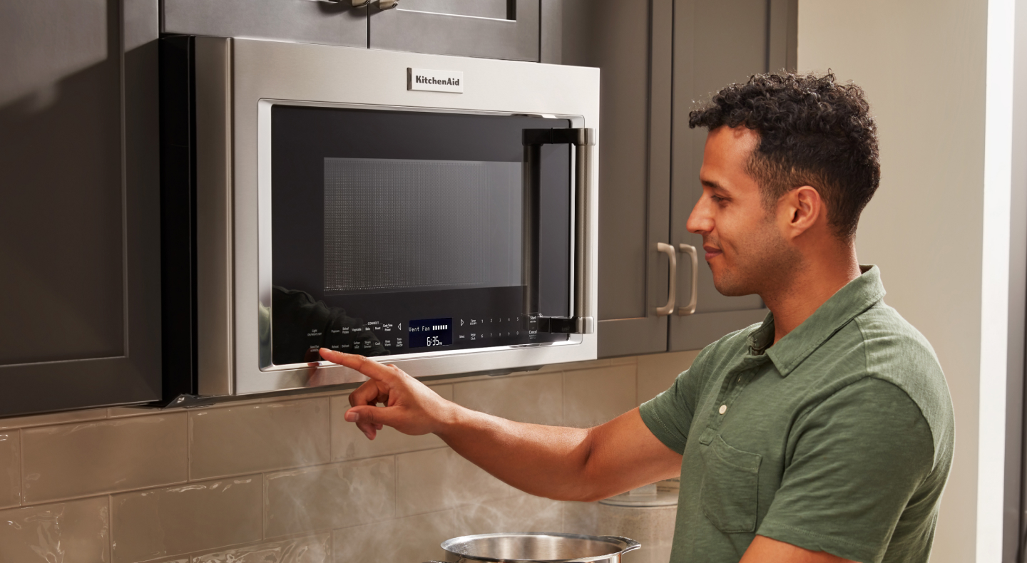 Person opening microwave with plate of food in hand