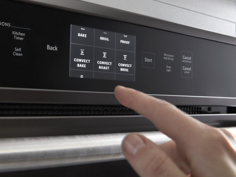 A finger choosing between different settings on a KitchenAid® oven