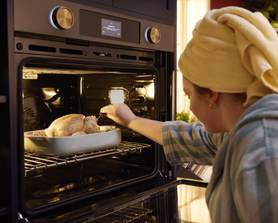 A person checking the temperature of the turkey she has cooking in the oven