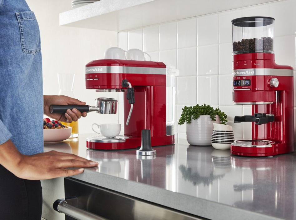 Woman using a red espresso coffee maker and grinder on countertop