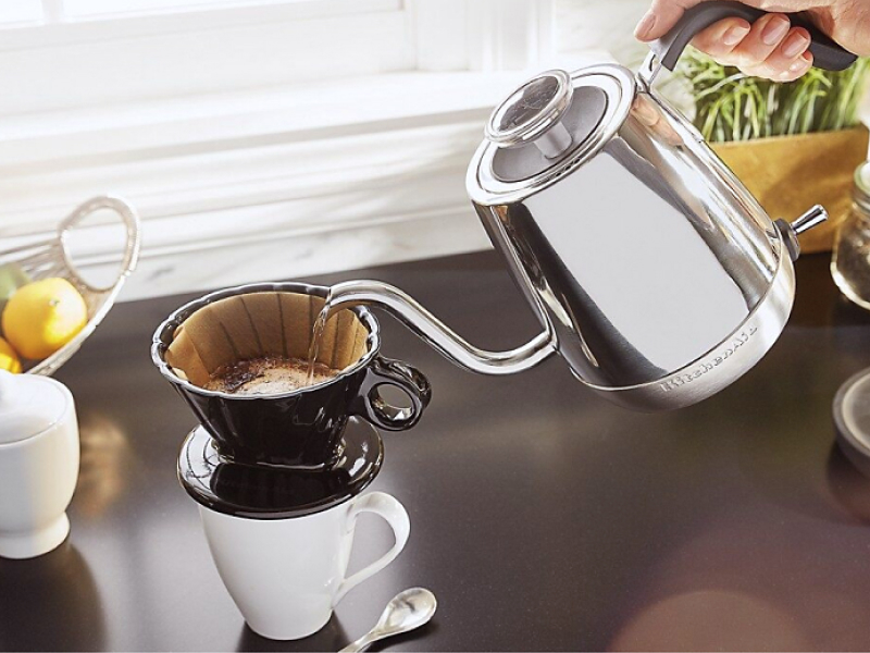 Maker pouring boiled water from gooseneck kettle into filter for pour over coffee Maker pouring boiled water from gooseneck kettle into filter for pour over coffee