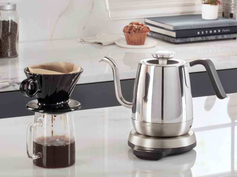 Silver KitchenAid® gooseneck kettle on white countertop with cup of pour over coffee Silver KitchenAid® gooseneck kettle on white countertop with cup of pour over coffee