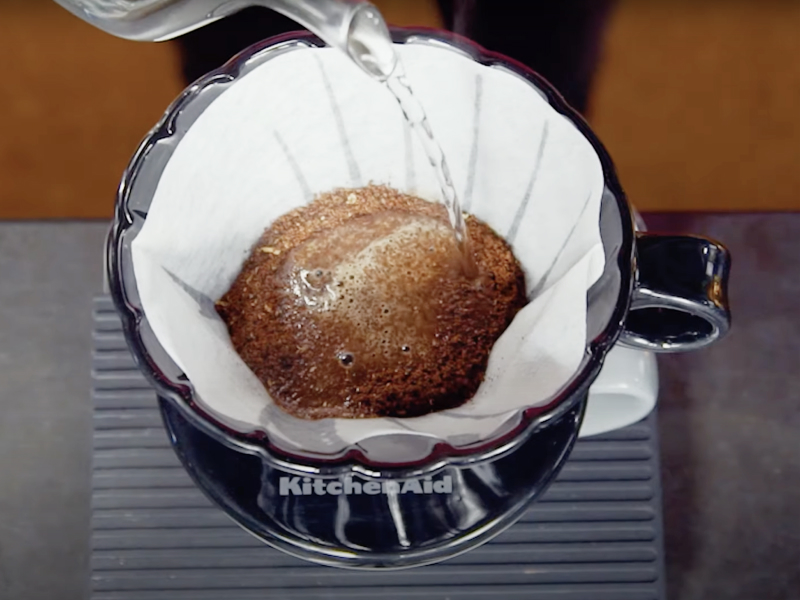 Top view of boiled water being added to coffee grounds in pour over filter