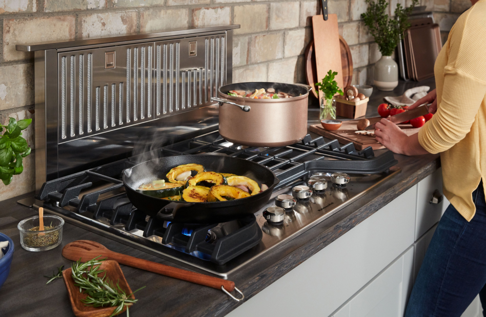 Downdraft ventilation behind a cooktop with multiple dishes on it Downdraft ventilation behind a cooktop with multiple dishes on it
