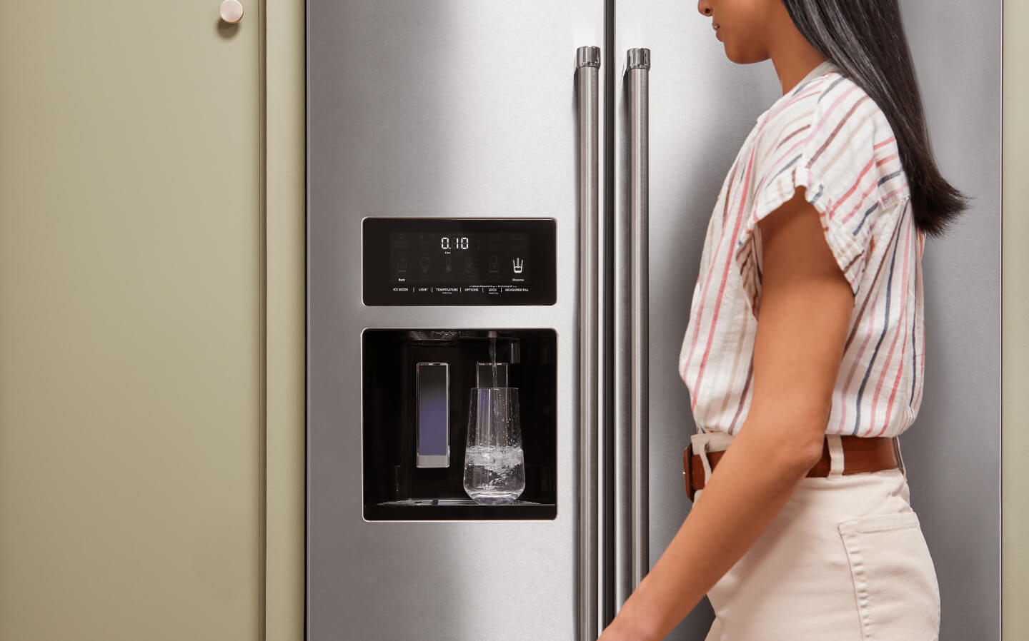 A person filling a glass of water using their refrigerator’s interior water dispenser A person filling a glass of water using their refrigerator’s interior water dispenser