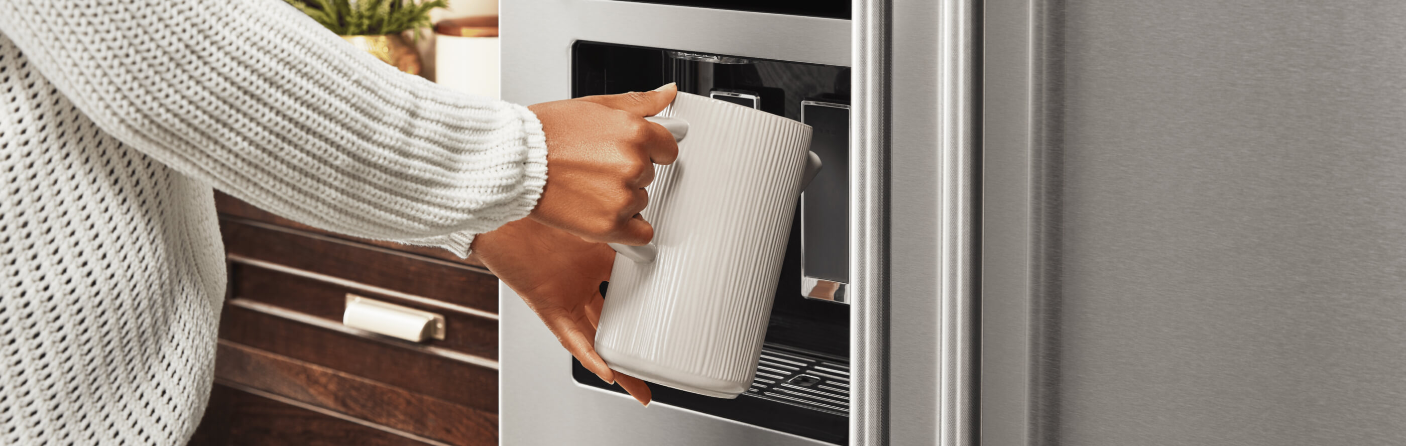 A person filling up a container at their refrigerator’s exterior ice and water dispenser