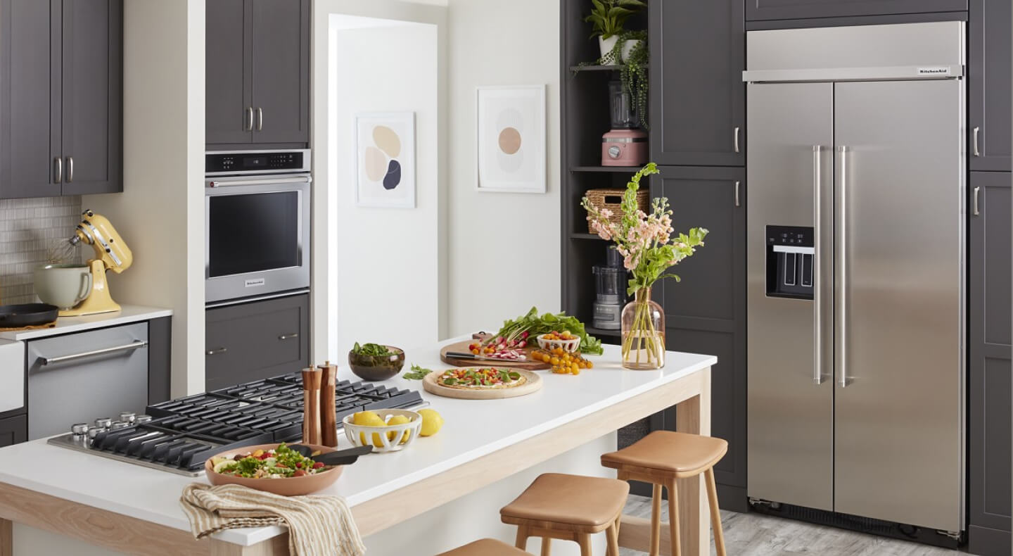 A kitchen with an island and a stainless steel side-by-side refrigerator A kitchen with an island and a stainless steel side-by-side refrigerator