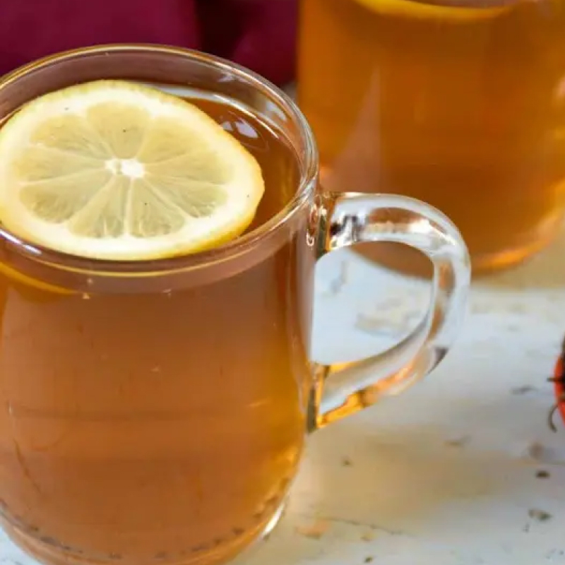 Glass mug of tea topped with a lemon slice