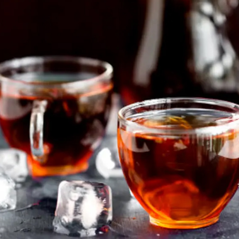 Two glass mugs of tea next to ice cubes