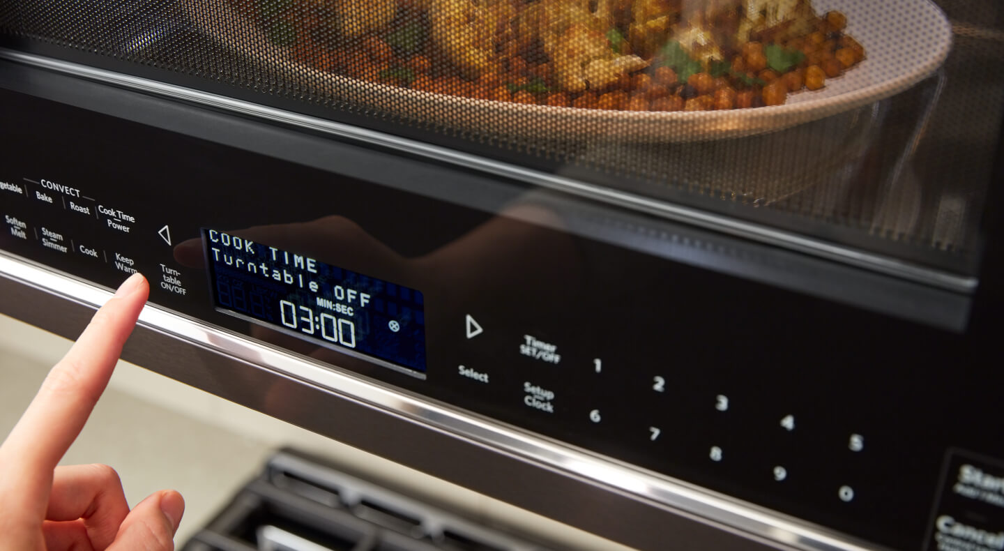 A person programming a setting on a KitchenAid® microwave A person programming a setting on a KitchenAid® microwave