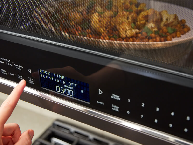 A person programming a setting on a KitchenAid® microwave A person programming a setting on a KitchenAid® microwave
